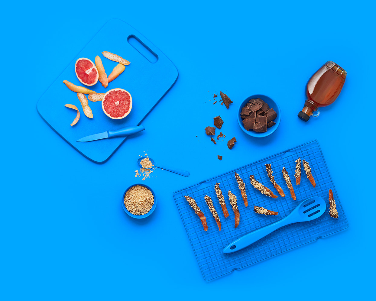 Blue background with candied fruit peels, and a bowl and spoon with maple flakes.